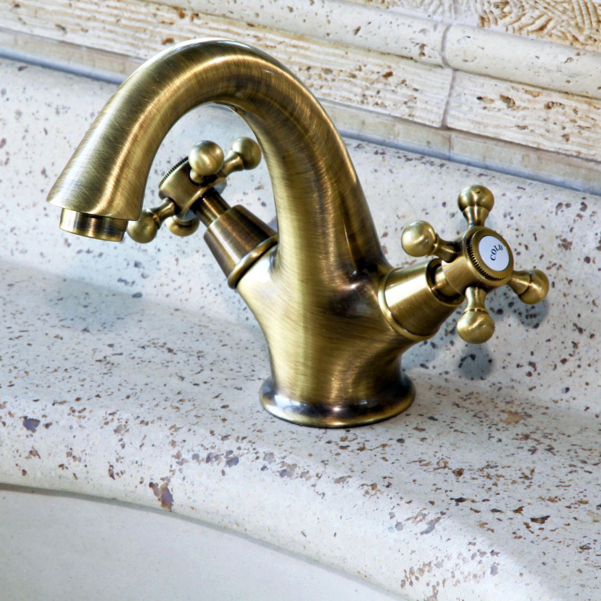 Brushed gold bathroom faucet on a speckled countertop.