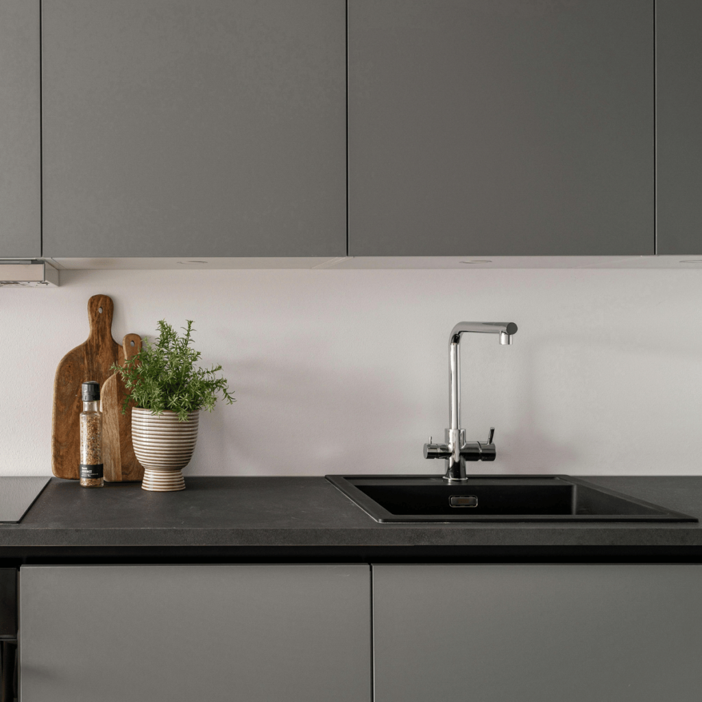 Concrete countertop with matte black sink and gray cabinets.