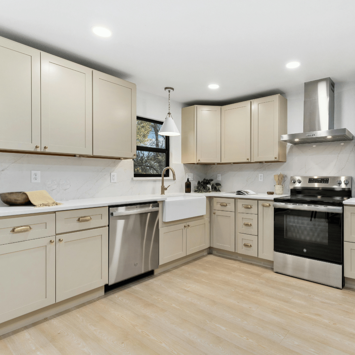 Custom kitchen cabinets in beige with white countertops and farmhouse sink.
