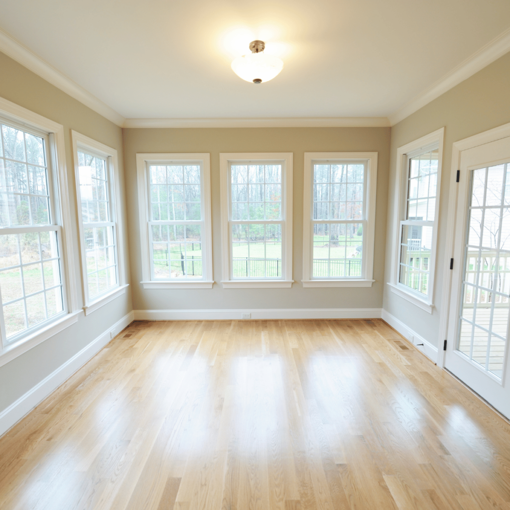 Bright sunroom with hardwood floors and multiple large windows.