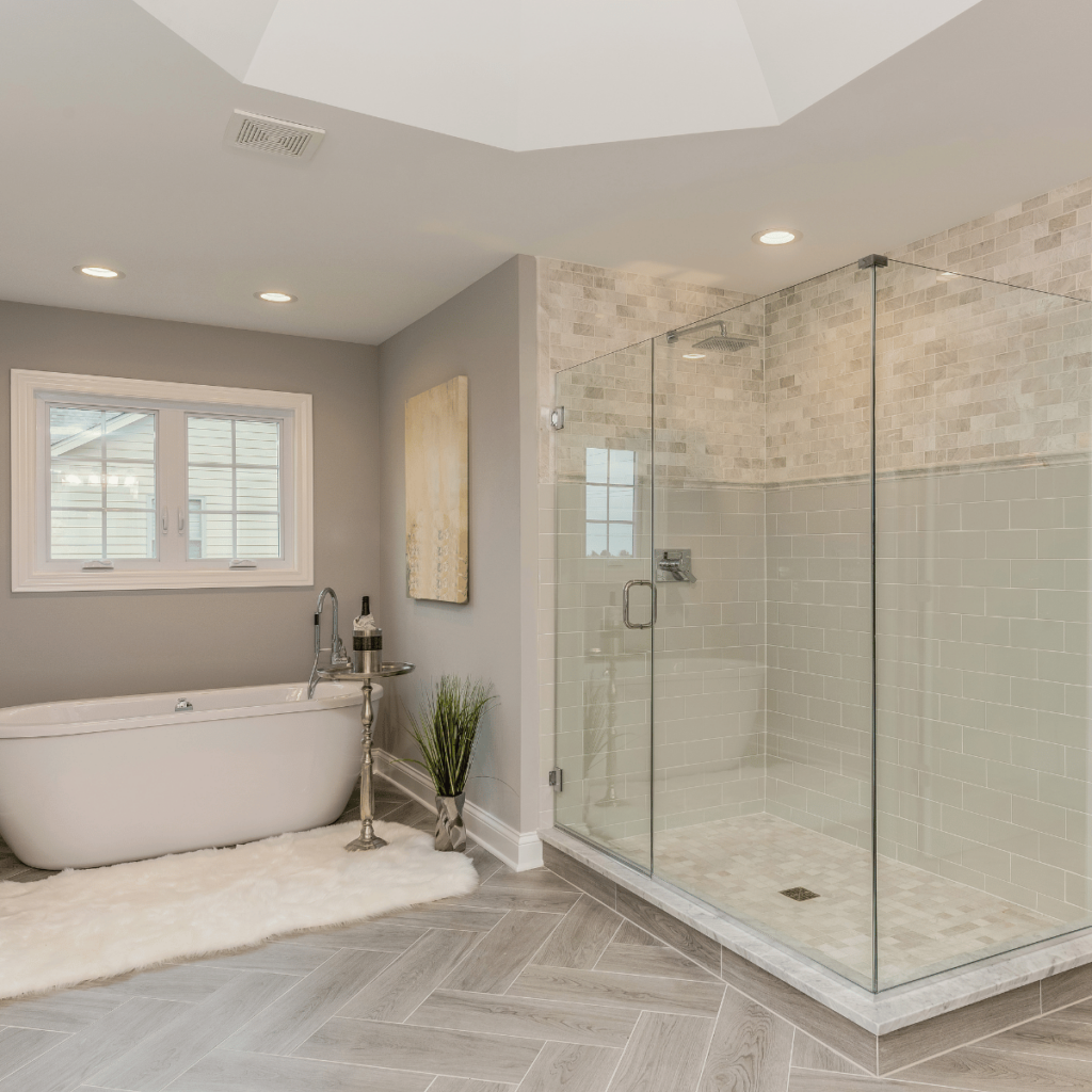 Bathroom with freestanding tub, glass walk-in shower, and light wood herringbone floor.