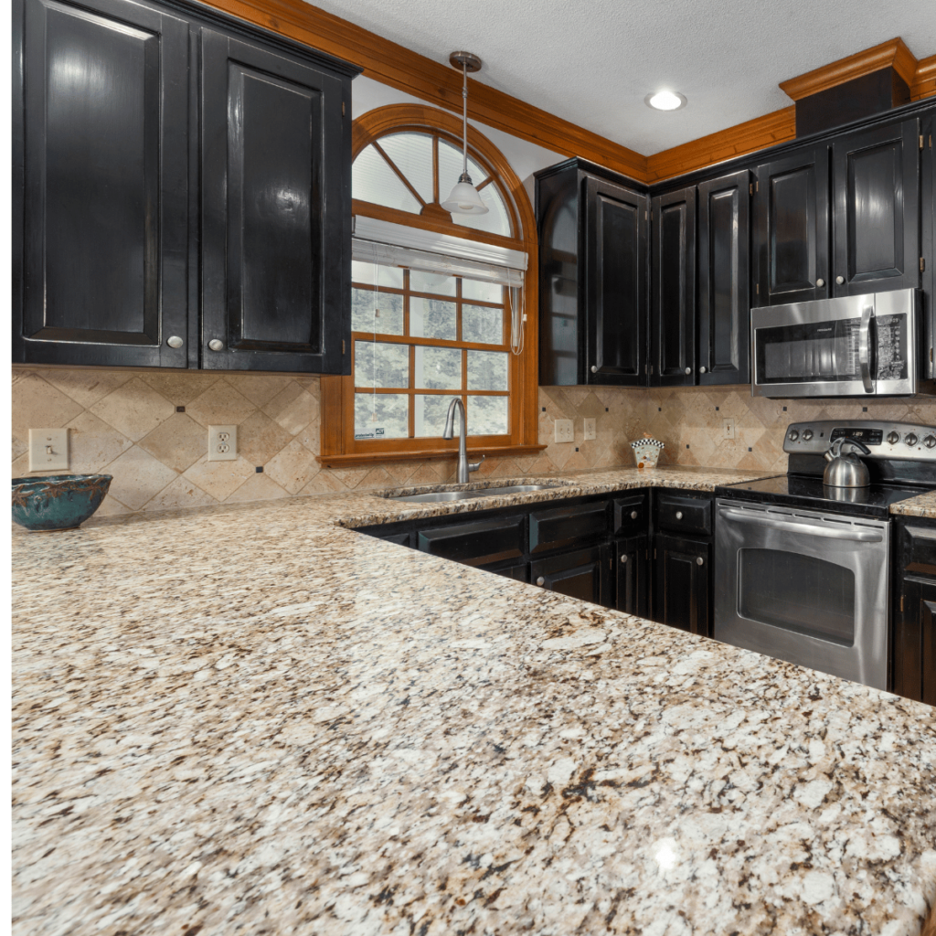Granite countertop with black cabinets and stainless steel appliances.
