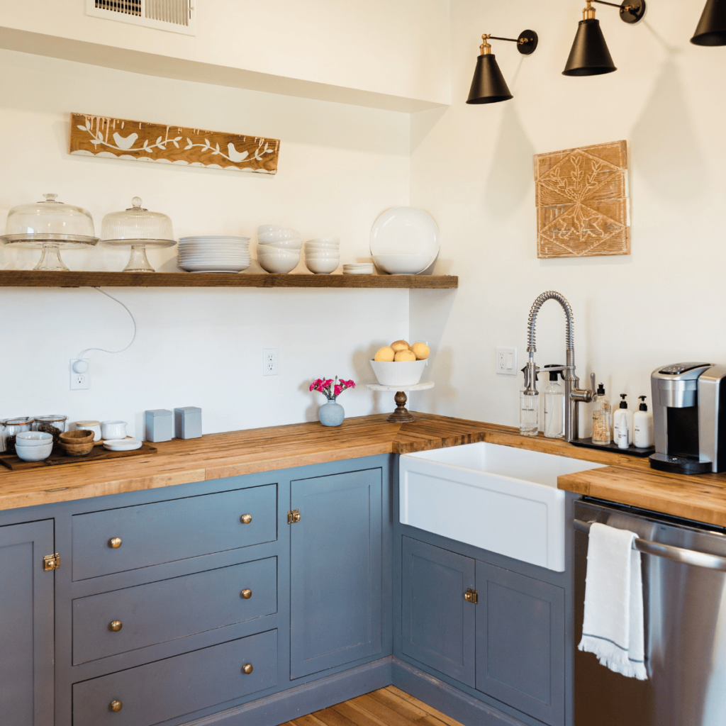 Farmhouse kitchen with blue cabinets, wood countertops, and open shelving.