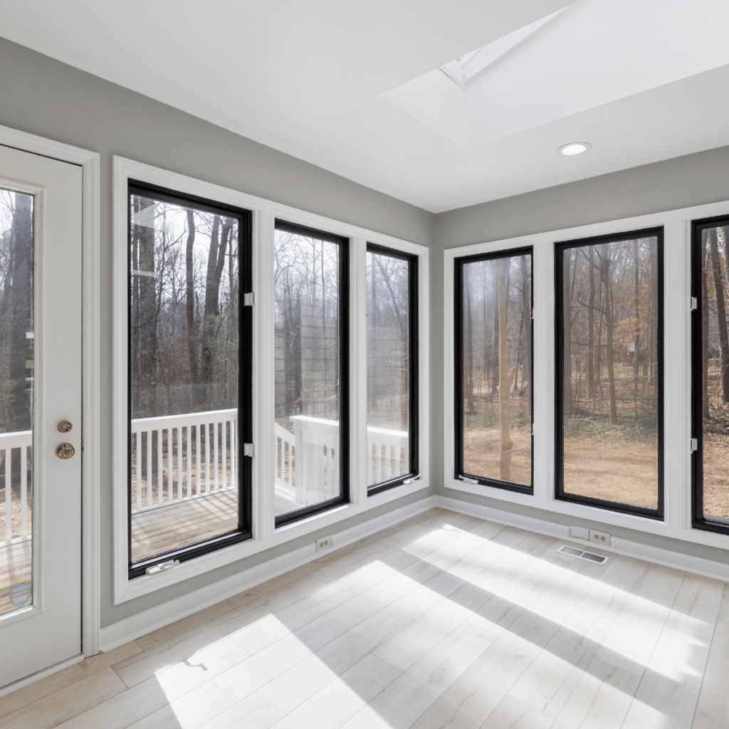 Modern sunroom with light wood floors and black-trimmed windows.