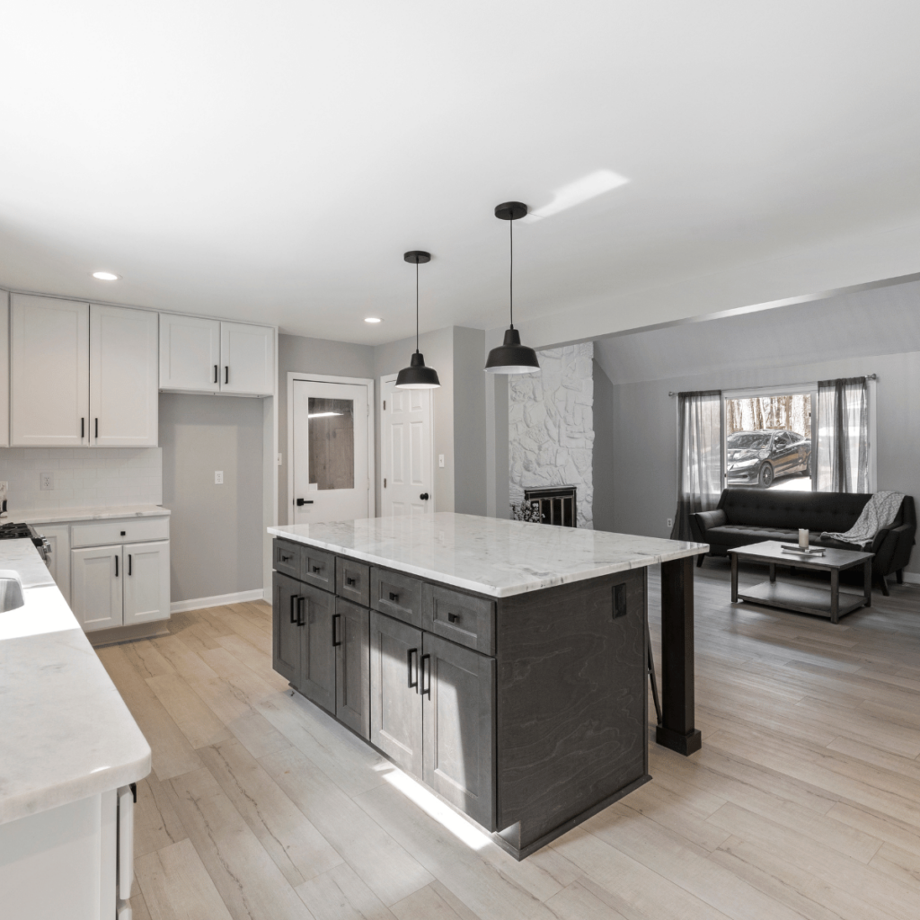 Kitchen with black island, white cabinets, and two black pendant lights.