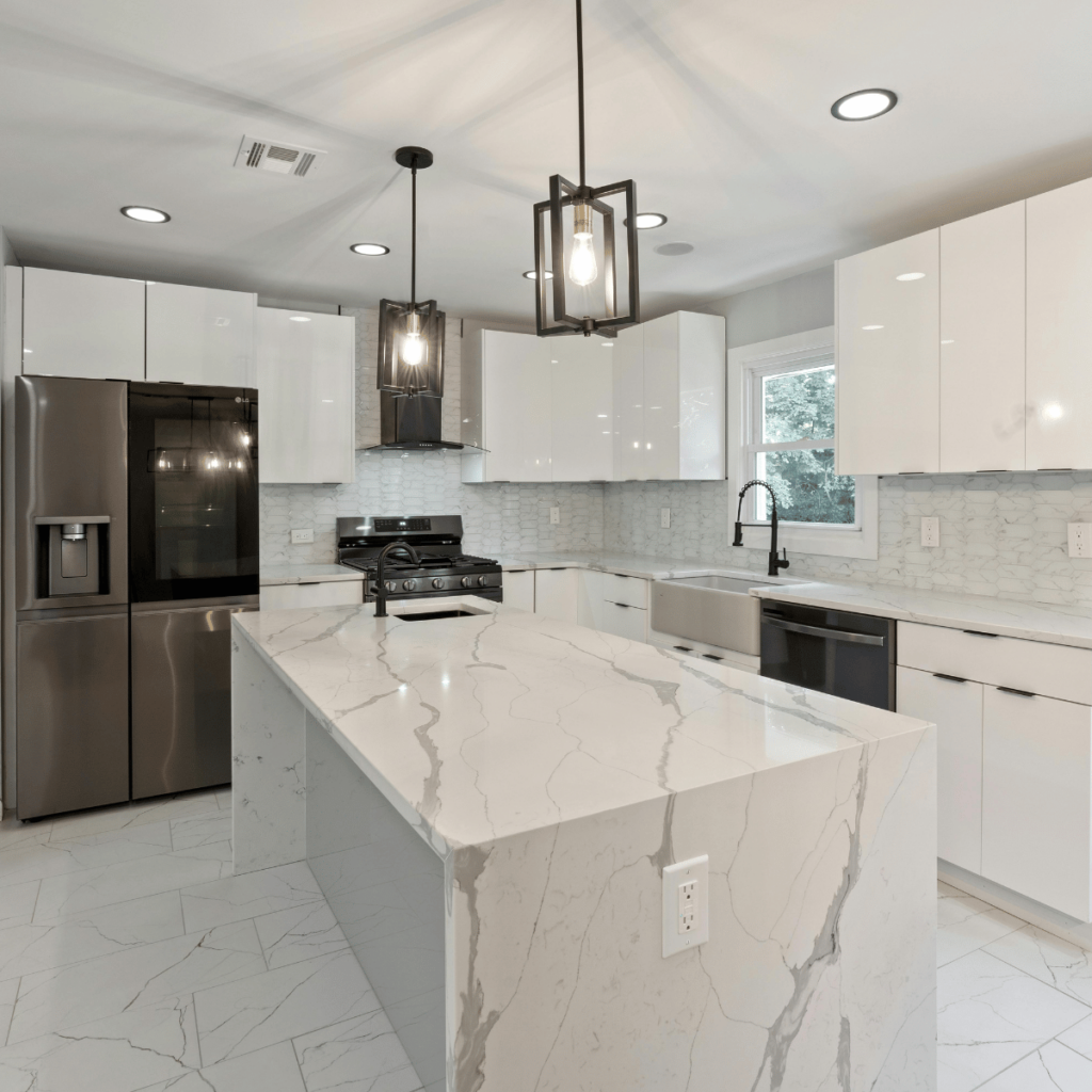 Quartz countertop island in a modern white kitchen with pendant lights.