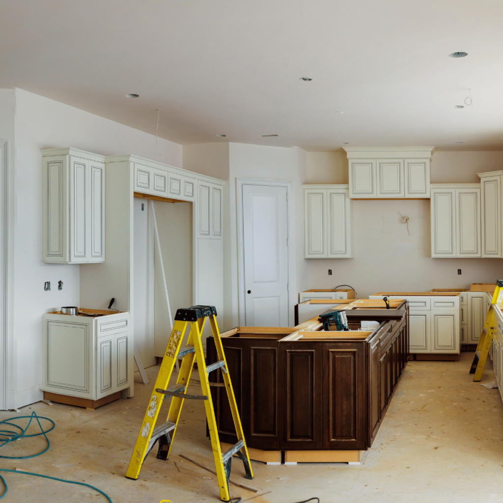 Kitchen remodel with white upper cabinets, dark island, and tools on site.