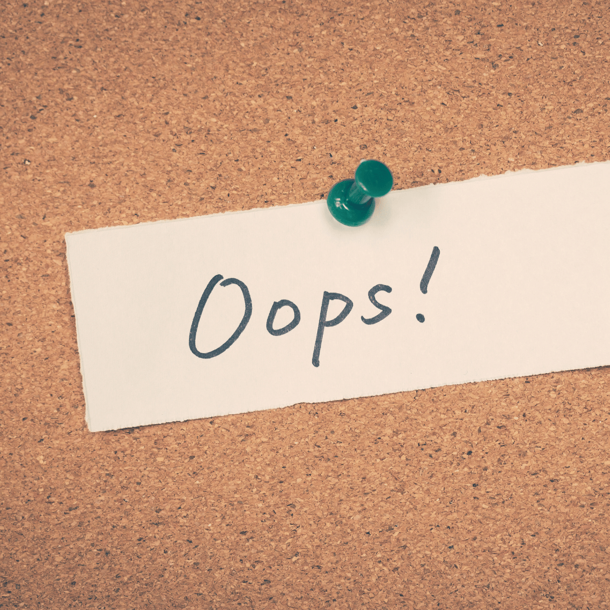 Oops written on a piece of paper tacked to a cork board.