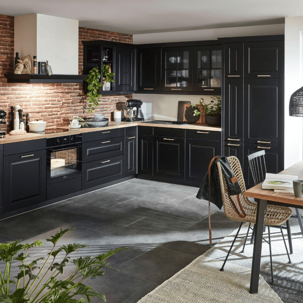 Black kitchen cabinets with brick backsplash and wood countertops.