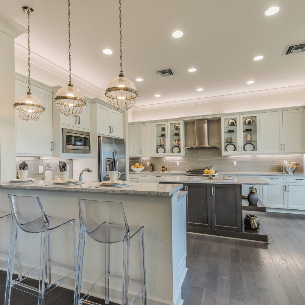 Bright kitchen with white cabinets, gray island, and globe pendant lights.